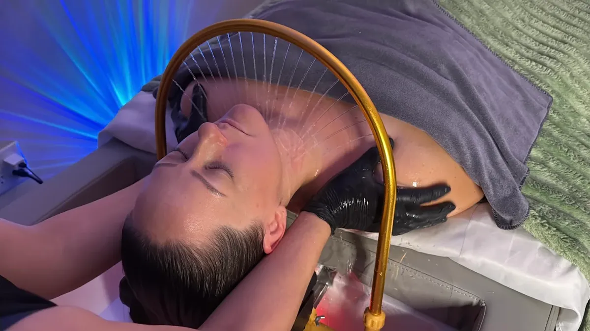 Warm-water rinse flowing from the gold hydrotherapy arch during a Soul scalp care